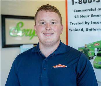 male smiling with red hair, brown eyes, and a navy blue SERVPRO shirt on