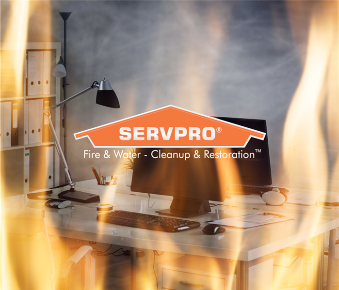 Office desk with computer and lamp and paperwork with flames around it. SERVPRO logo over the center of it.