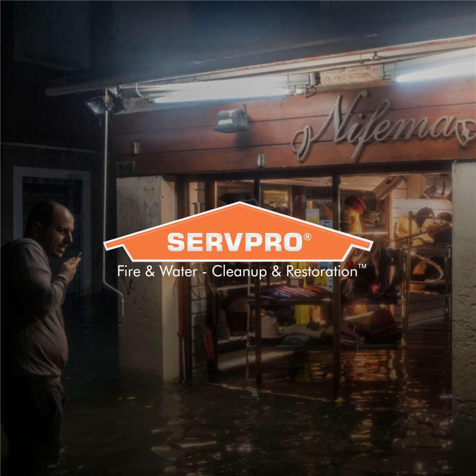 man on the phone calling help about his flooded store with SERVPRO logo over the top of the photo