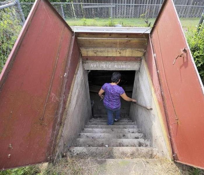 underground storm shelter with a woman going downstairs